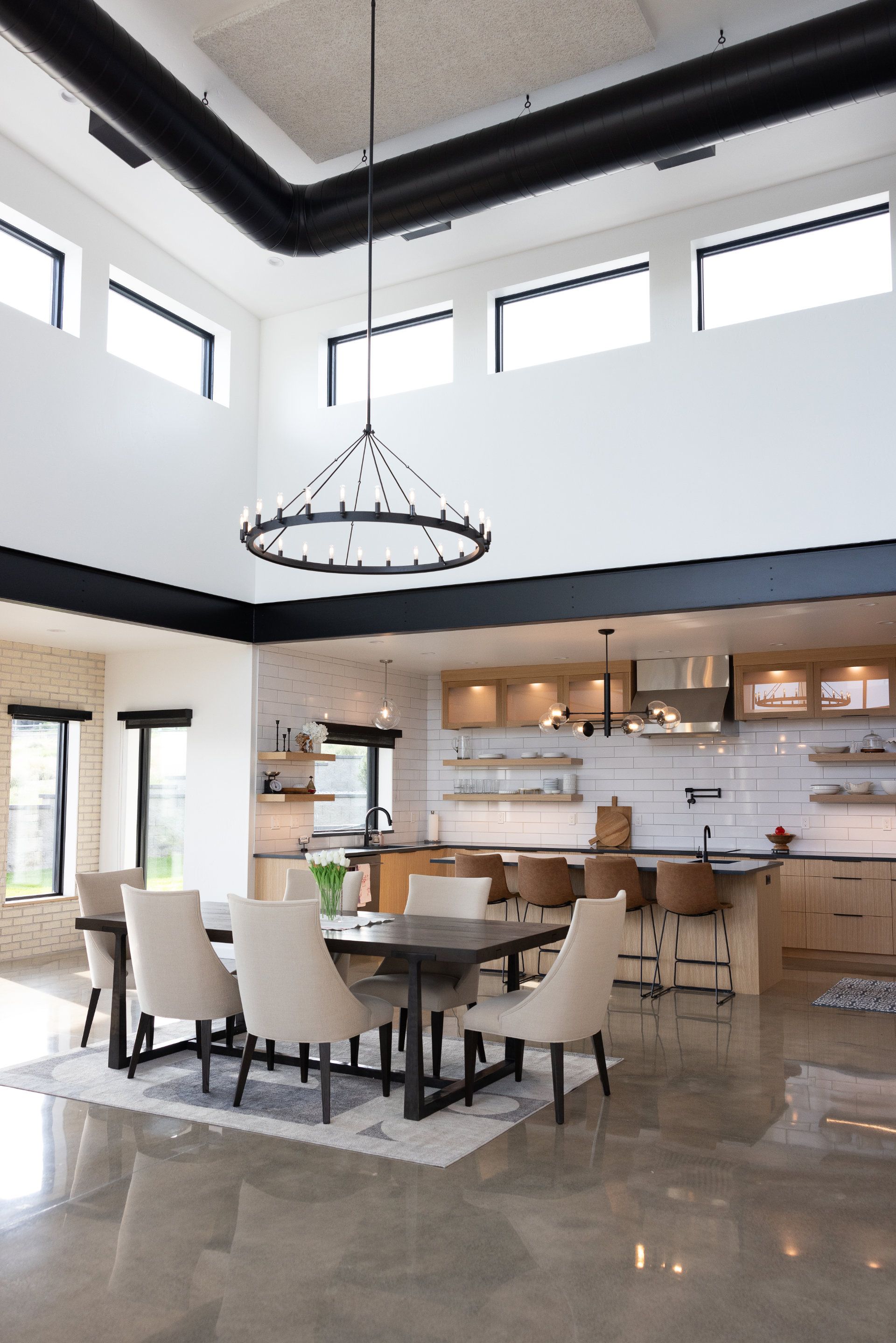 A dining room with a table and chairs and a kitchen in the background.
