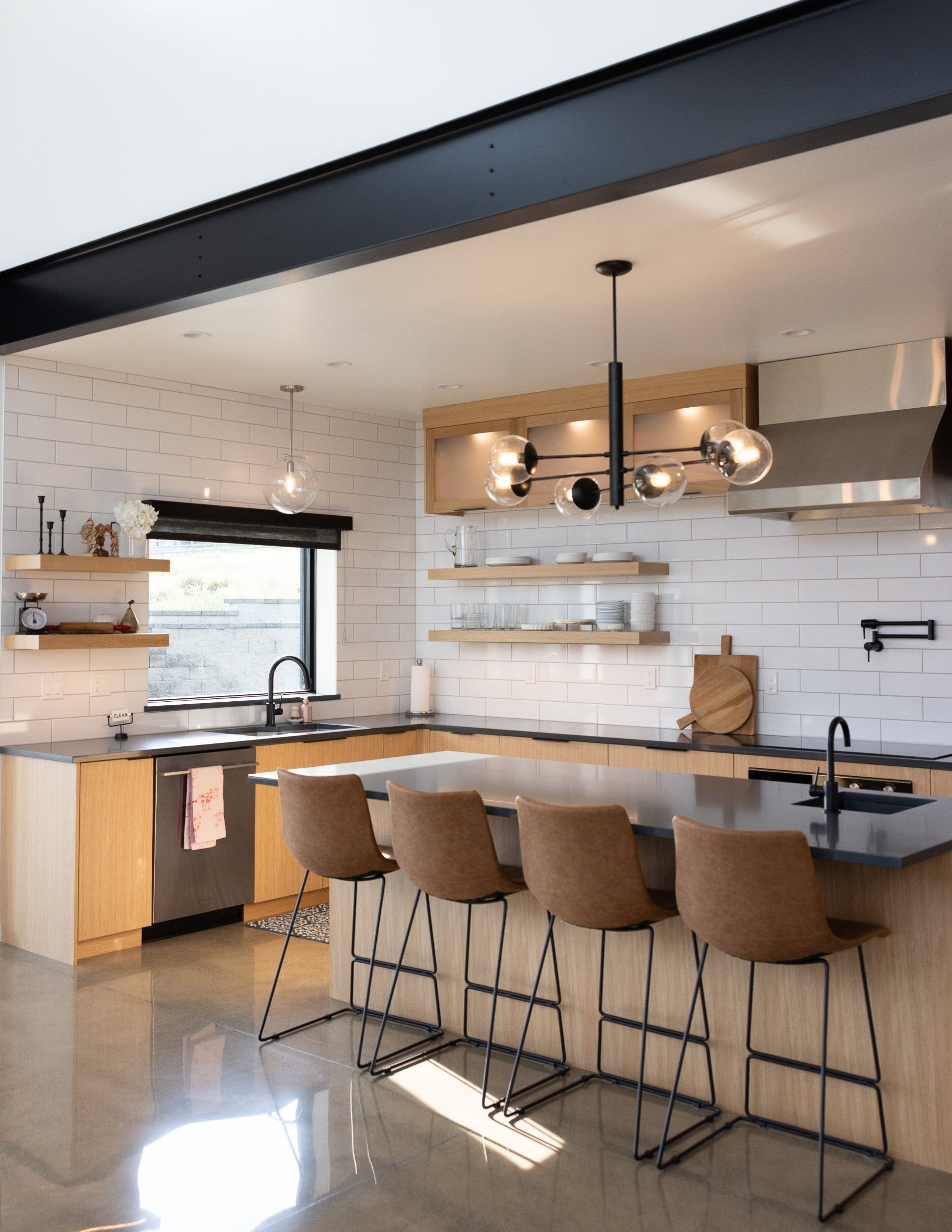 A kitchen with a large island , stools and a sink.
