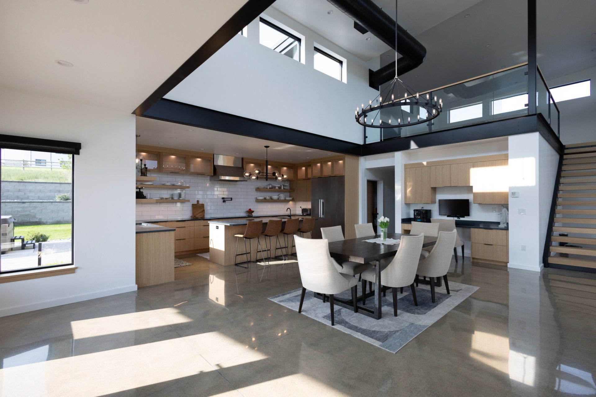 A dining room with a table and chairs and a kitchen in the background