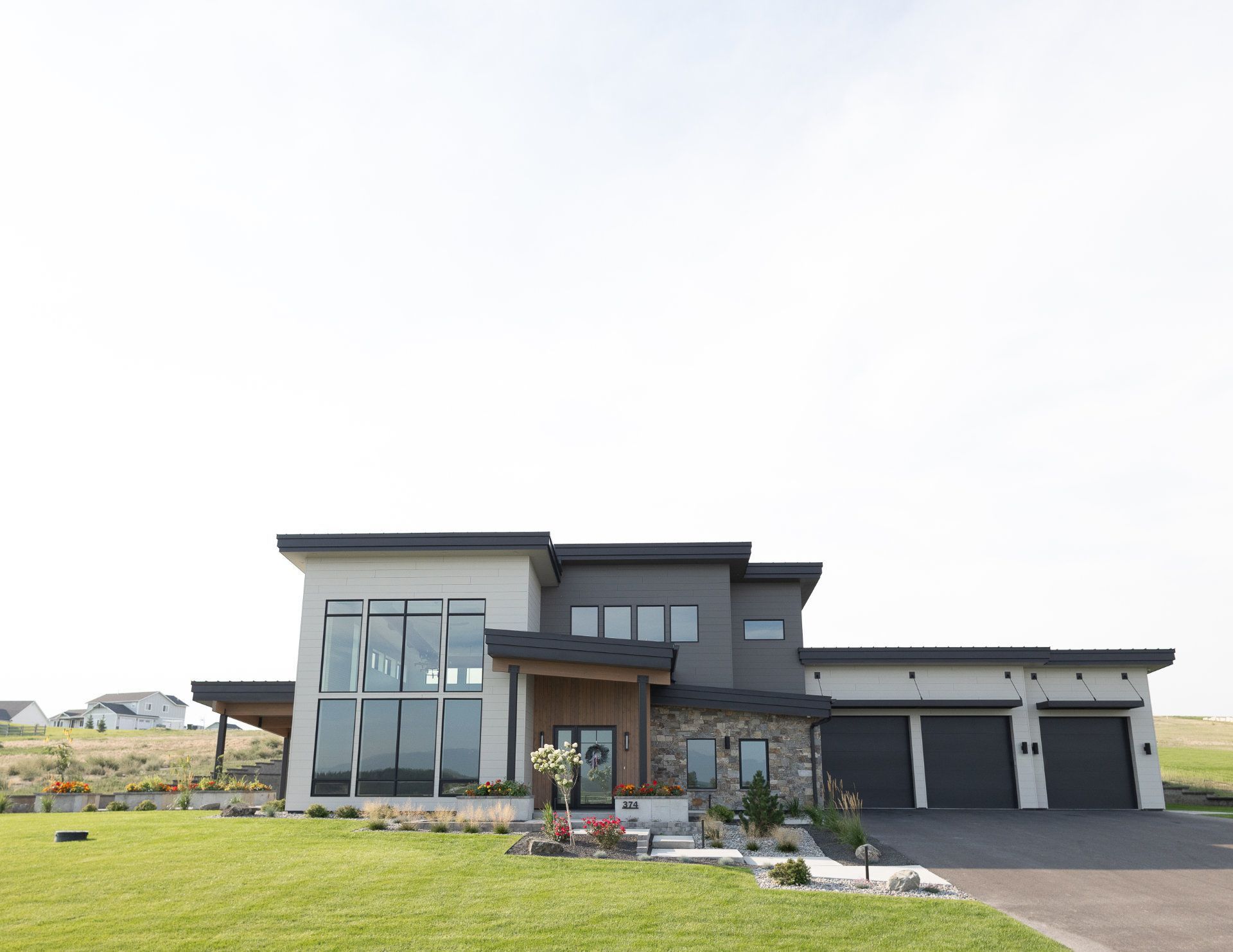 A large modern house with a lot of windows and a large driveway.