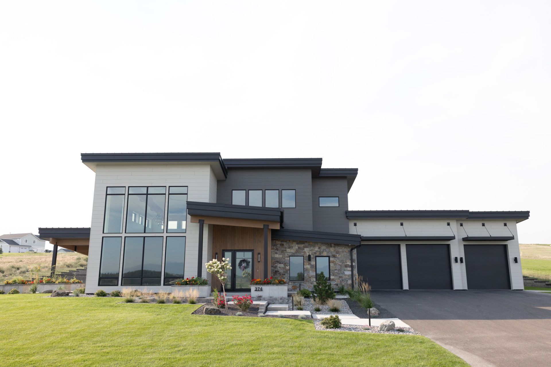 A large modern house with a lot of windows is sitting on top of a lush green field.