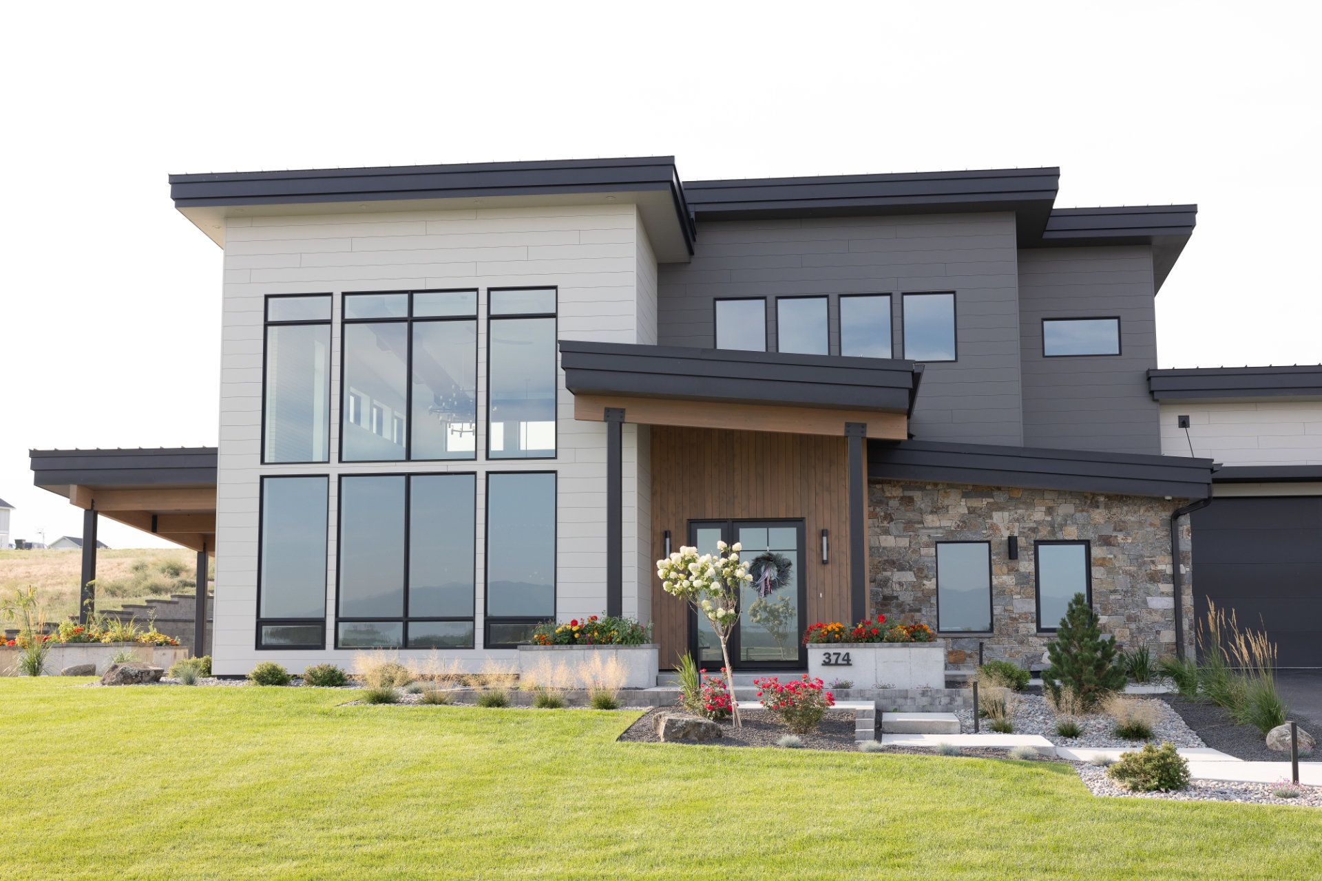 A large house with a lot of windows is sitting on top of a lush green field.