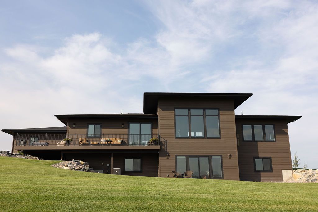 A large house sits on top of a grassy hill