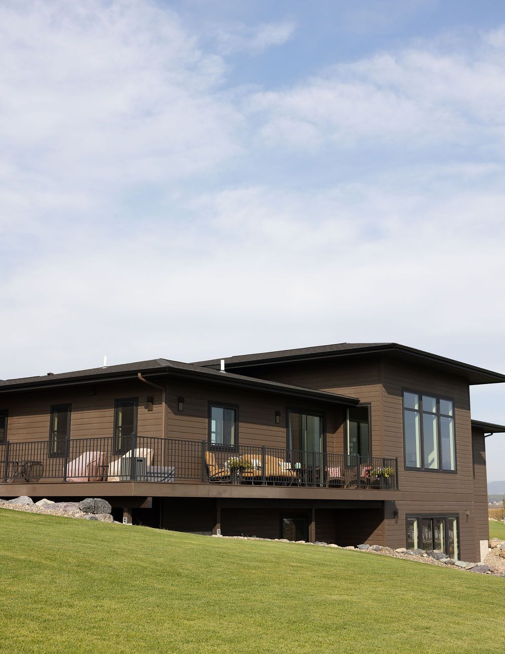A large house with a balcony sits on top of a grassy hill.