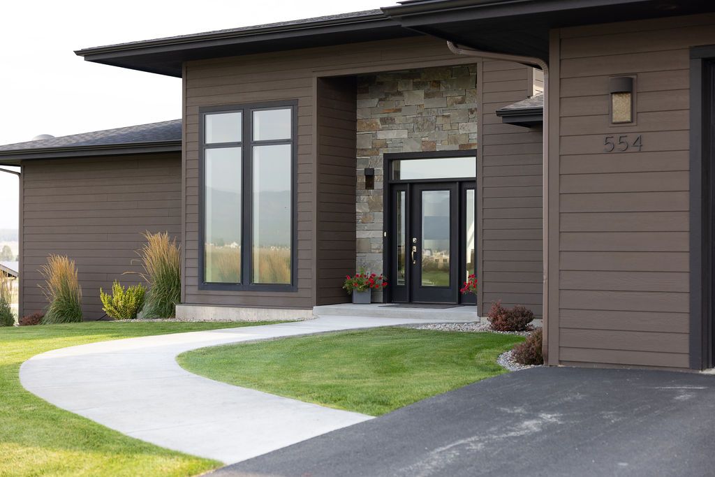 A large brown house with a driveway leading to it.