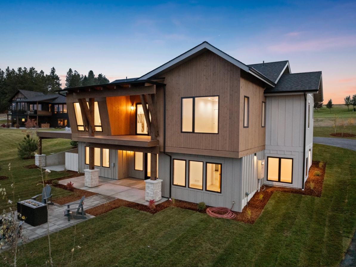 A large house with a lot of windows is sitting on top of a lush green field.