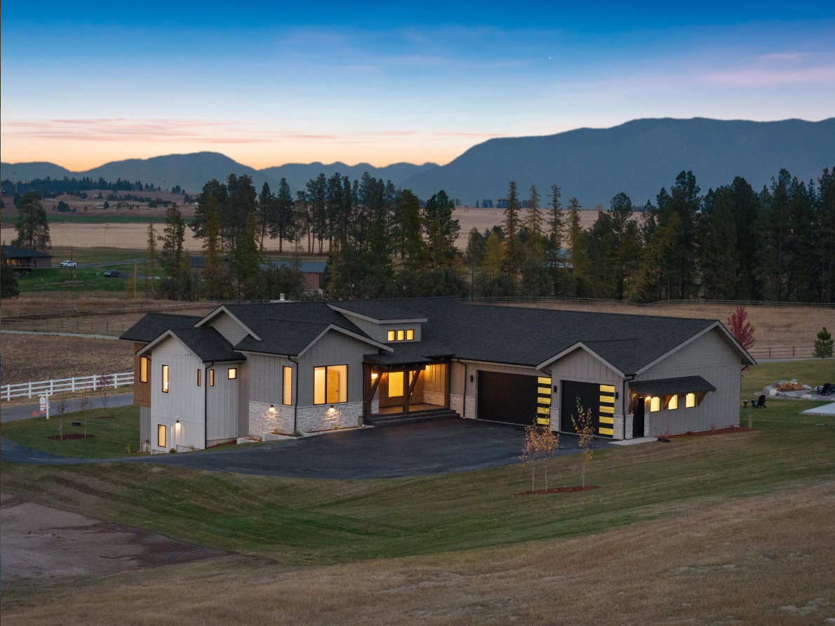 An aerial view of a large house with mountains in the background.