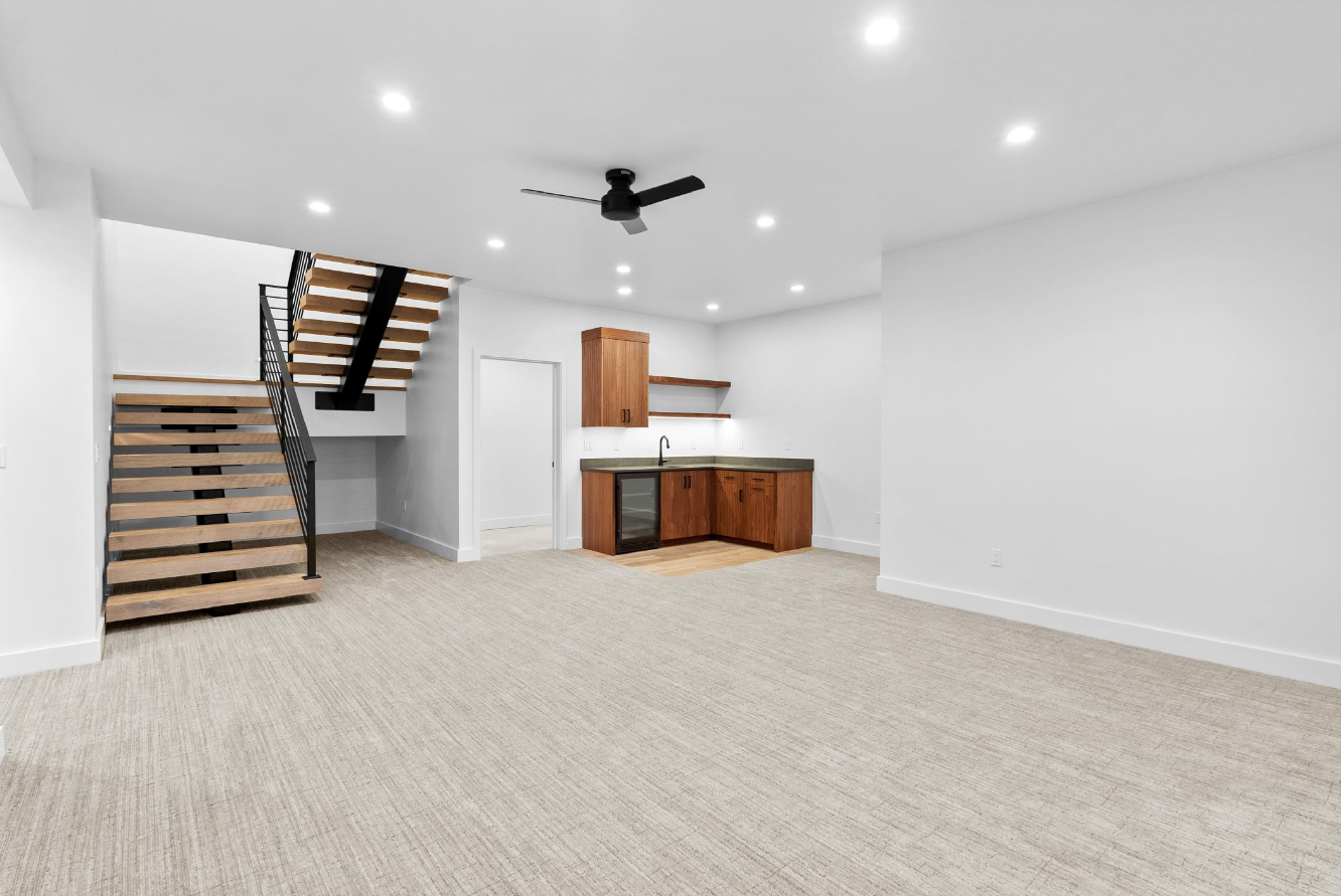 An empty room with a staircase and a ceiling fan.