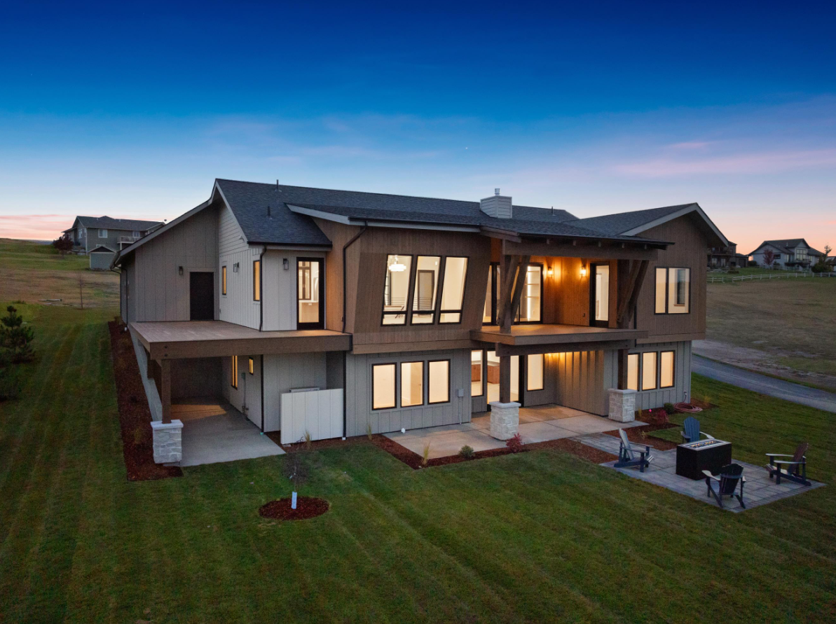 A large house with a lot of windows is sitting on top of a lush green field.