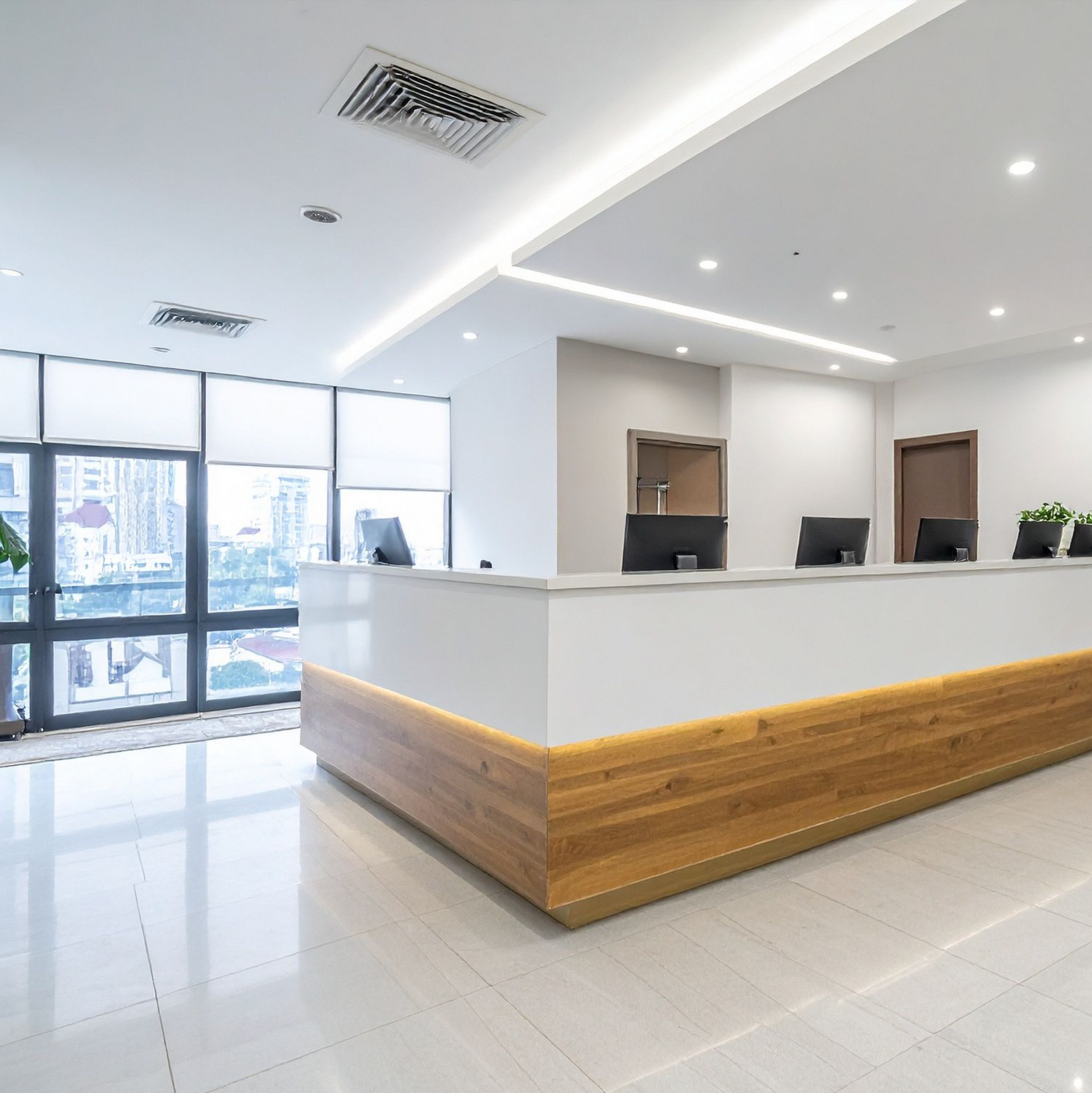 Modern, bright office reception area with long white counter and wood paneling.