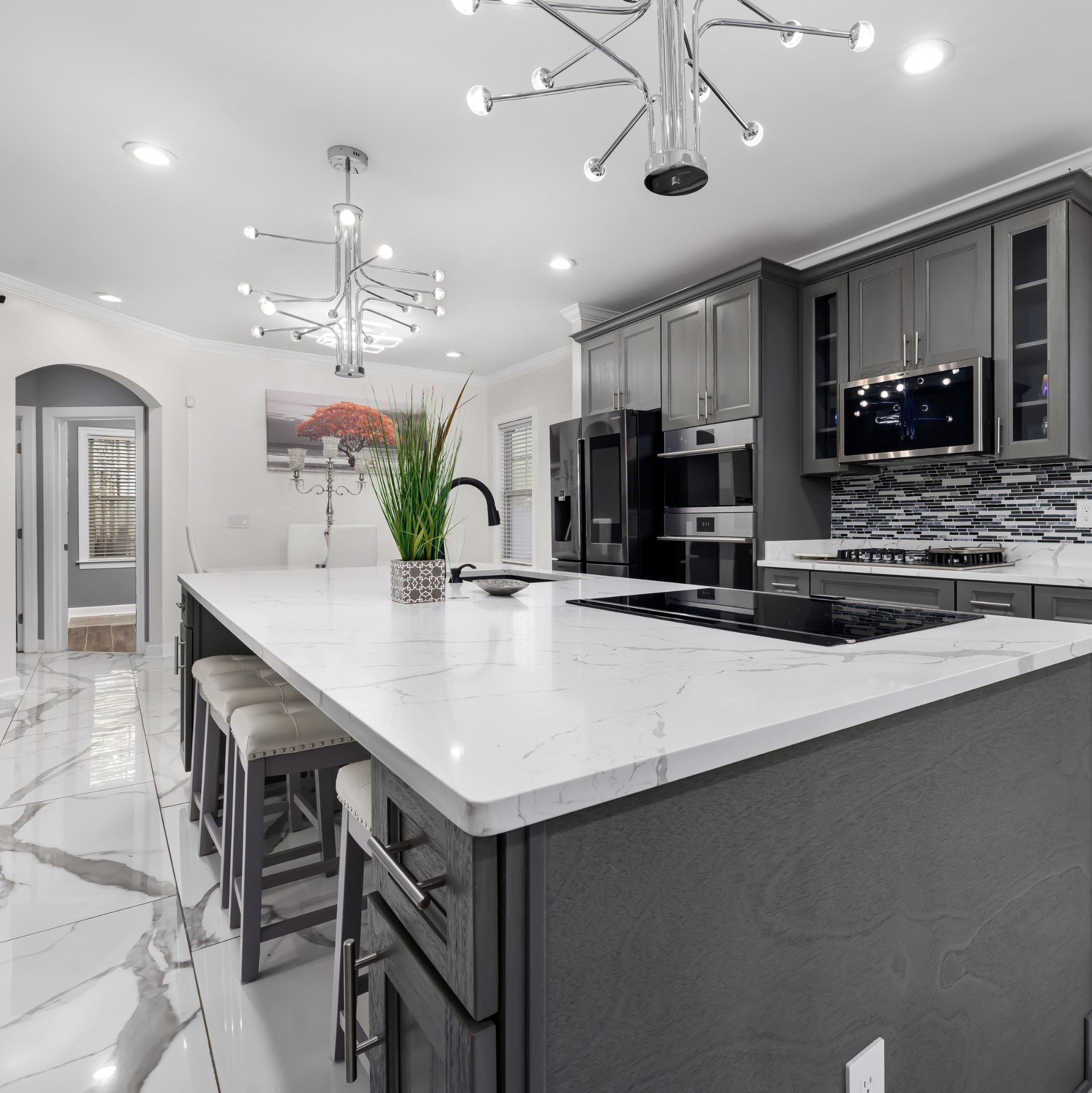 Modern kitchen with gray cabinets, white countertops, and marble flooring.