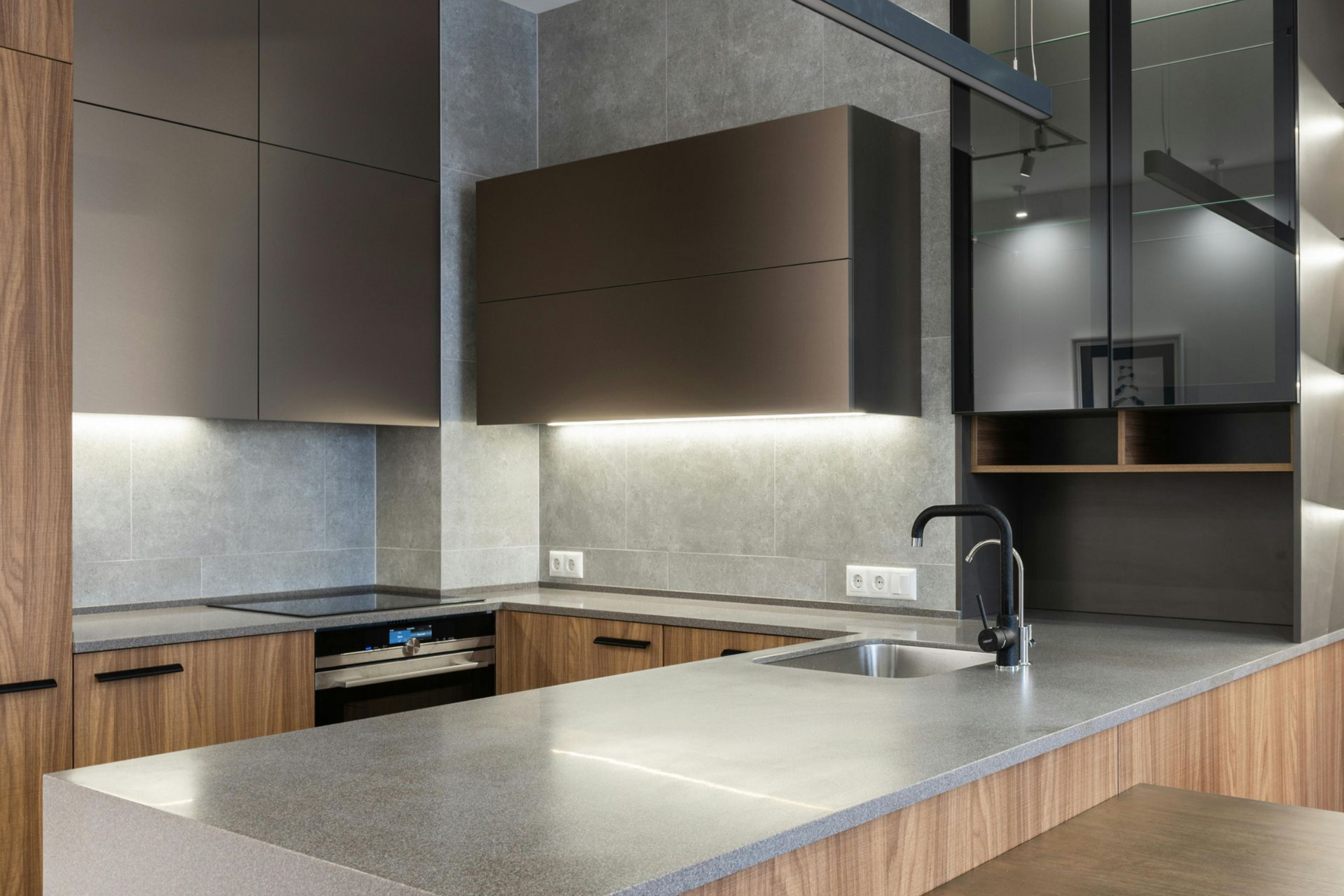 Modern kitchen with wood and dark gray cabinetry, countertops, and backsplash.