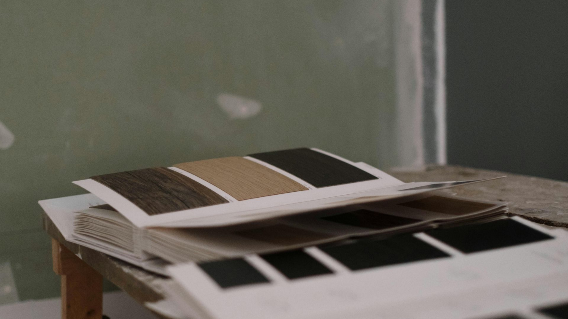 Color swatches open on a table in front of a painted wall.