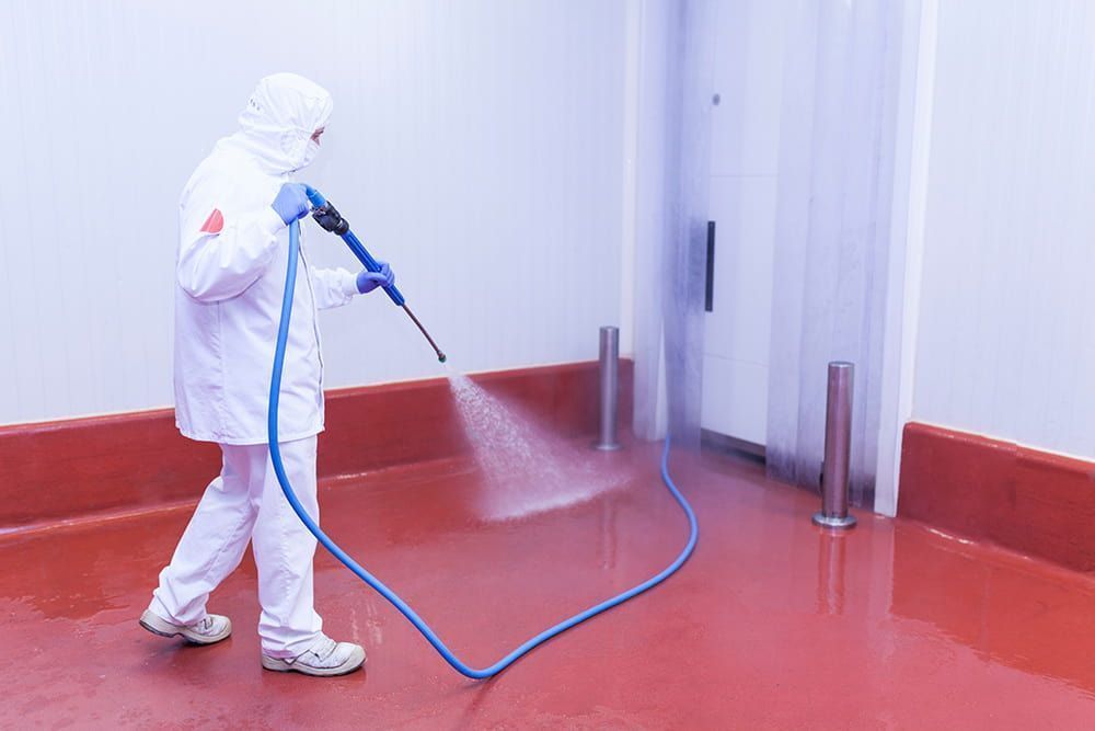 A Worker in White Protective Gear Sprays Cleaning Liquid — South Coast Pressure Washer in Gerringong, NSW