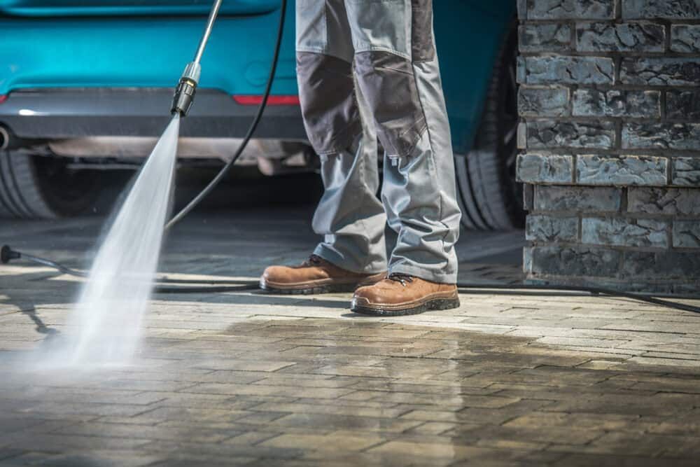 A Person in Work Pants and Boots Uses a Pressure Washer — South Coast Pressure Washer in Shellharbour, NSW