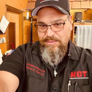 A bearded man wearing glasses, a black cap, and a black shirt with 