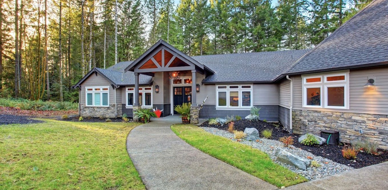A large house with a walkway leading to it is surrounded by trees.