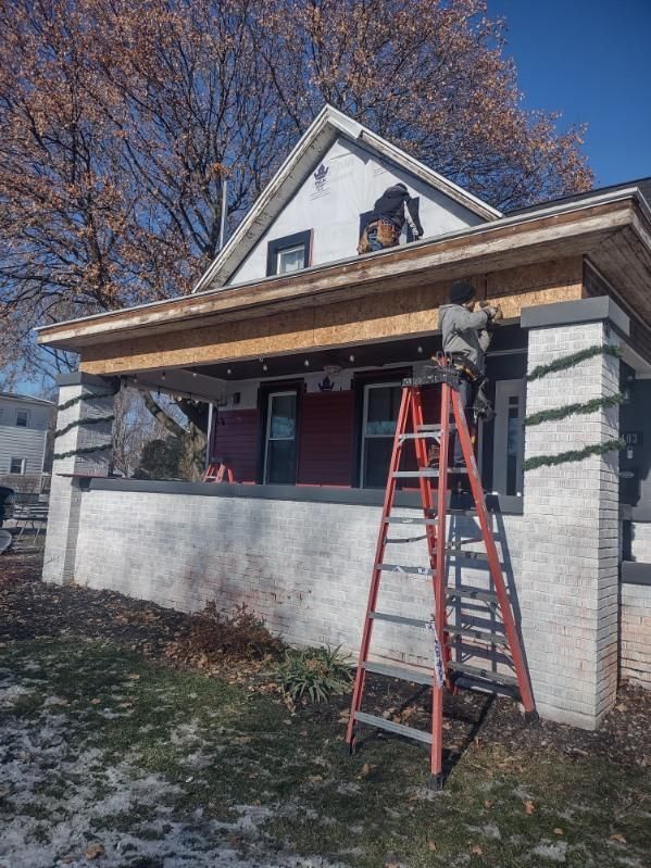 A man standing on a ladder in front of a house