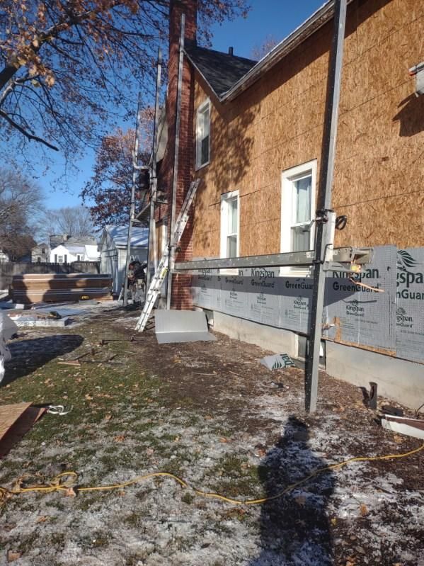 A house is being remodeled with a ladder on the side of it.