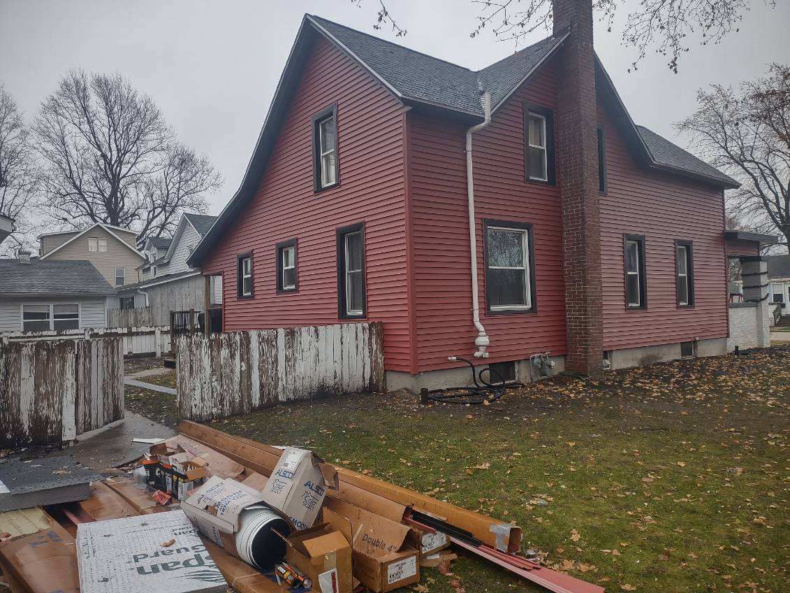 A large red house with a lot of junk in front of it.