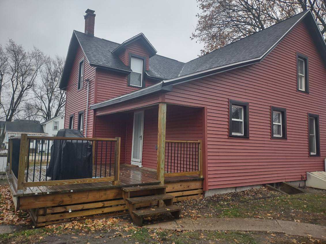 A red house with a wooden deck in front of it.