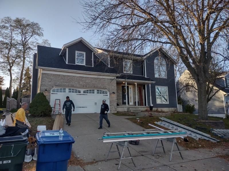 A group of people are standing in front of a large house.