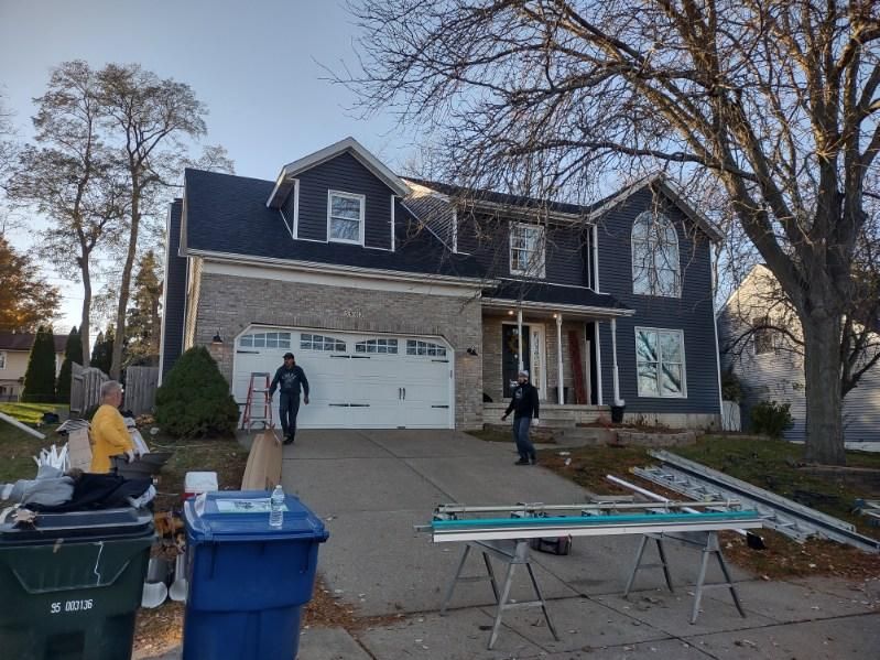 A large house with a blue trash can in front of it.