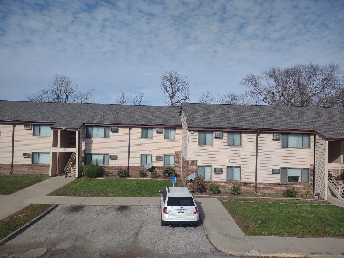 A white suv is parked in front of a apartment building