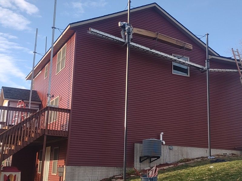 A red house with a ladder on the side of it.
