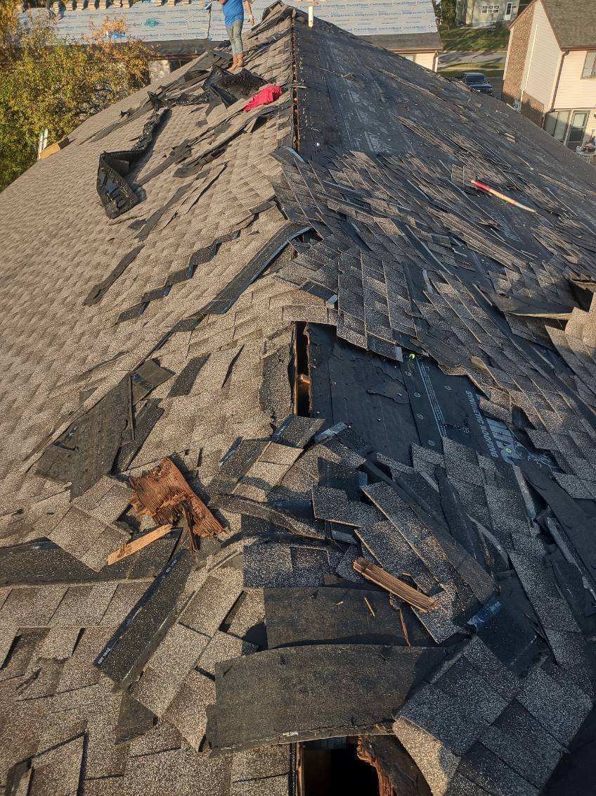 A roof with a lot of shingles missing and a hole in it.