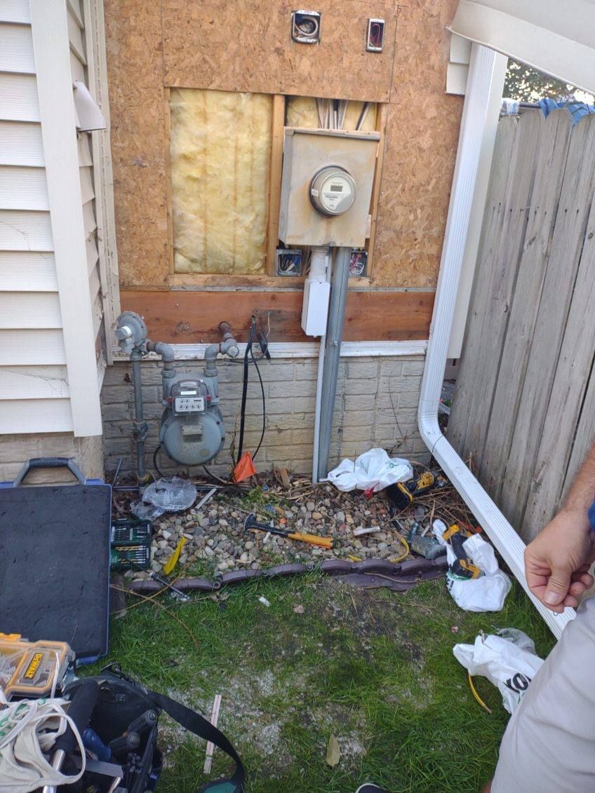 A man is standing in front of a house with a meter on the side of it.