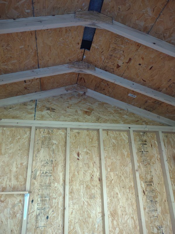 A shed is being built with plywood and wooden beams