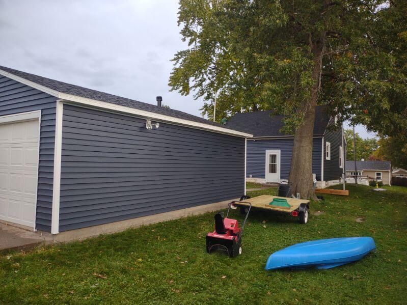 A blue kayak is sitting in the grass in front of a house.