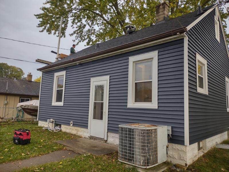 A small house with a blue siding and a red vacuum cleaner in front of it.