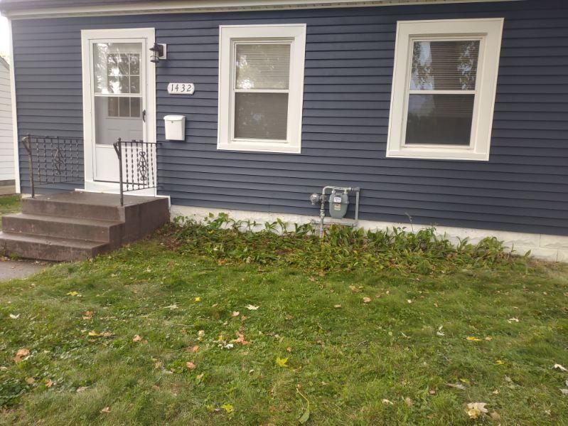 A blue house with a white door and windows is sitting on top of a lush green lawn.
