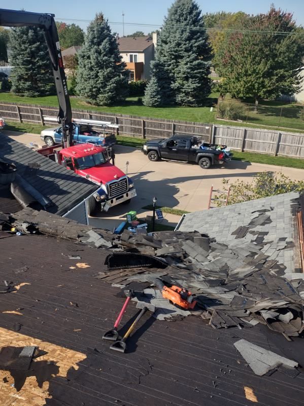 A crane is being used to remove shingles from a roof