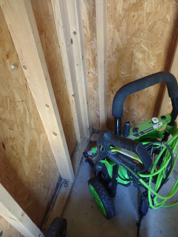 A green bicycle is sitting in a wooden shed.