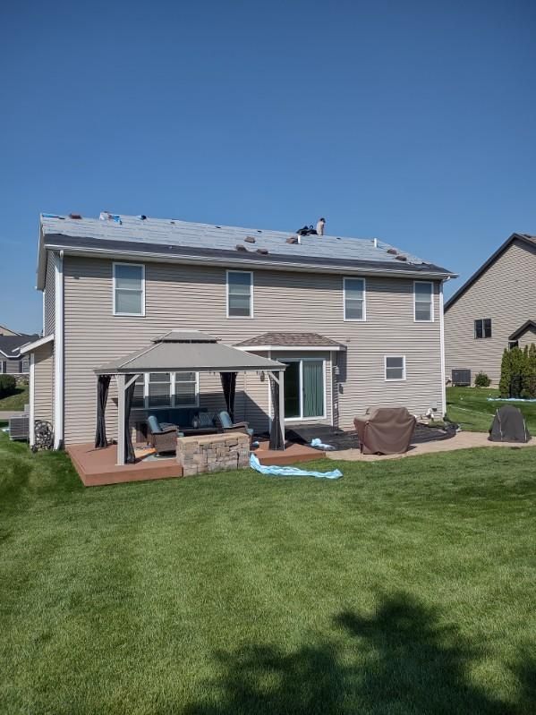 The backyard of a house with a gazebo and a fire pit.