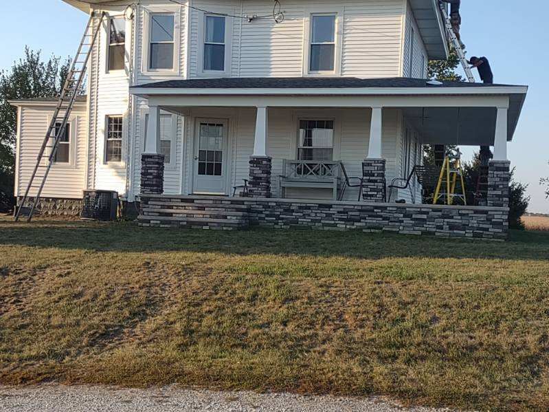 A man is working on the roof of a white house.