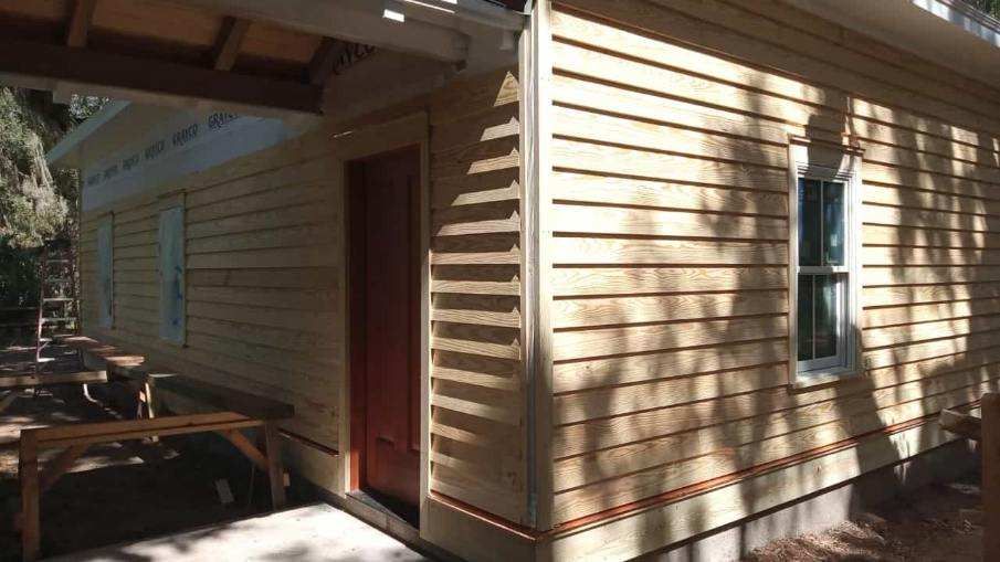 A house with a red door and a white window is being built.