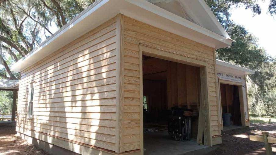 A wooden garage with a white roof is being built.