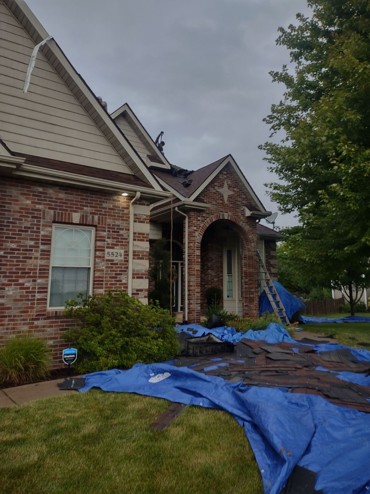 A brick house with a blue tarp on the ground in front of it.