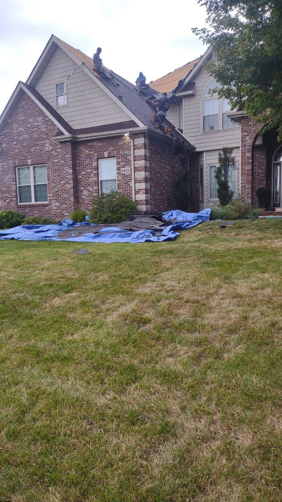 A large brick house with a roof that is being repaired.
