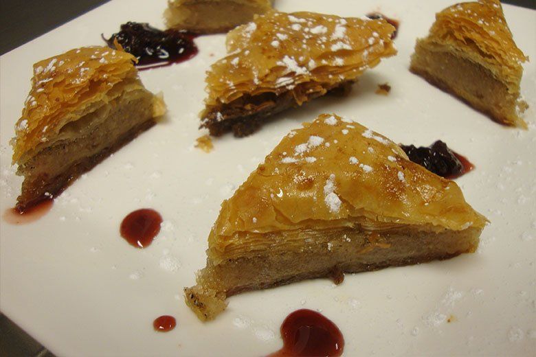 A white plate topped with slices of baklava and powdered sugar