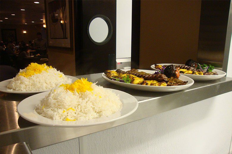 Three plates of food are sitting on a stainless steel counter.