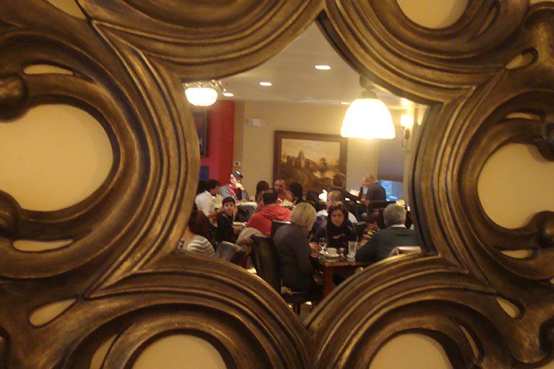 A mirror shows a group of people sitting at tables in a restaurant