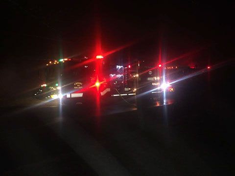 A fire truck is parked on the side of the road at night.