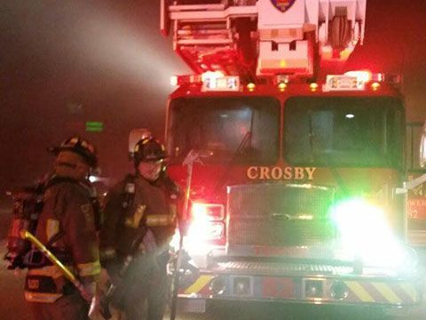 Two firefighters stand in front of a Crosby fire truck