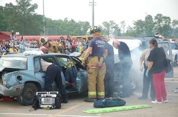 A group of people are standing around a wrecked car during a public demonstration.