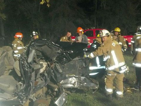 A group of firefighters are working on a wrecked vehicle